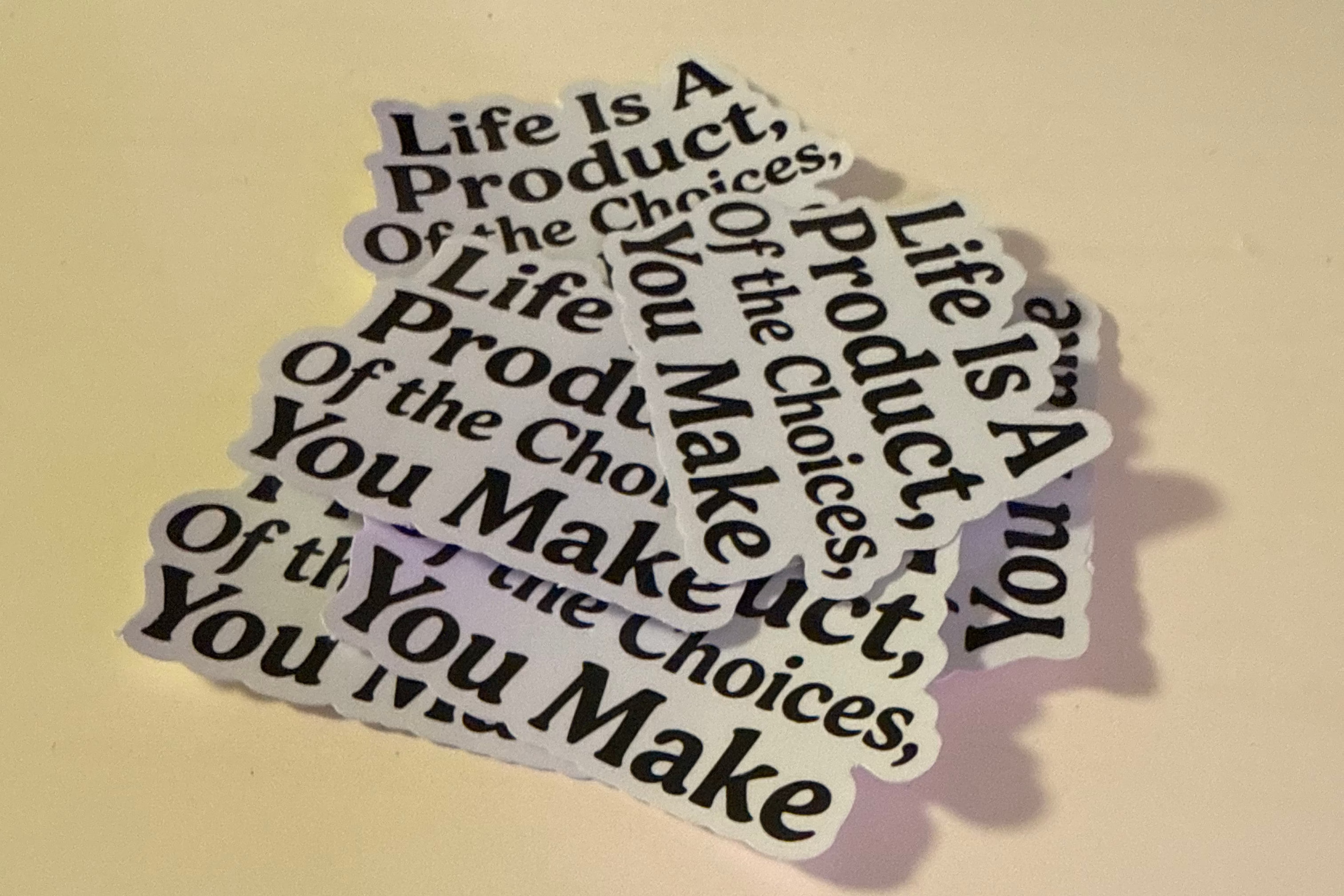 Sticker with 'Life Is A Product, Of The Choices, You Make' text on a beige background